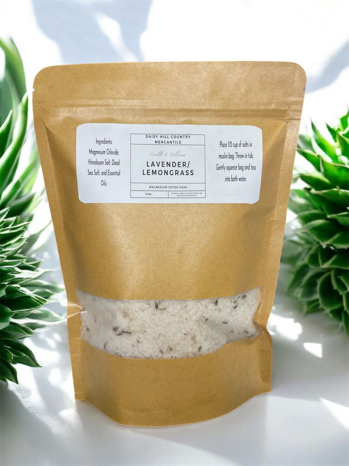 A package of magnesium detox soak with visible crystals of salt through the semi-transparent window of the paper bag, labeled with 'Lavender Lemongrass' and net weight 1.5 lbs.