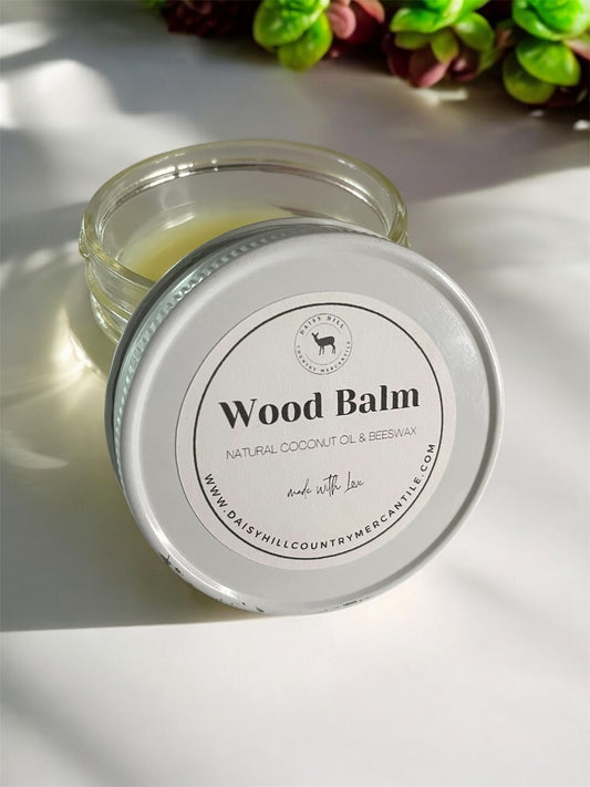 A 4 oz glass jar of Natural Wood Balm, placed on a wooden surface with a bright background.