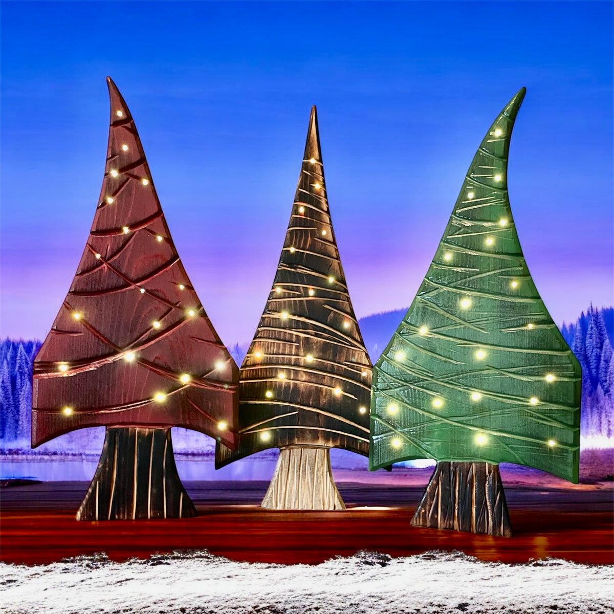 Three decorative trees with lights against a snowy landscape