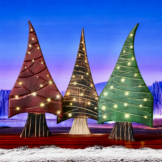 Three decorative trees with lights against a snowy landscape