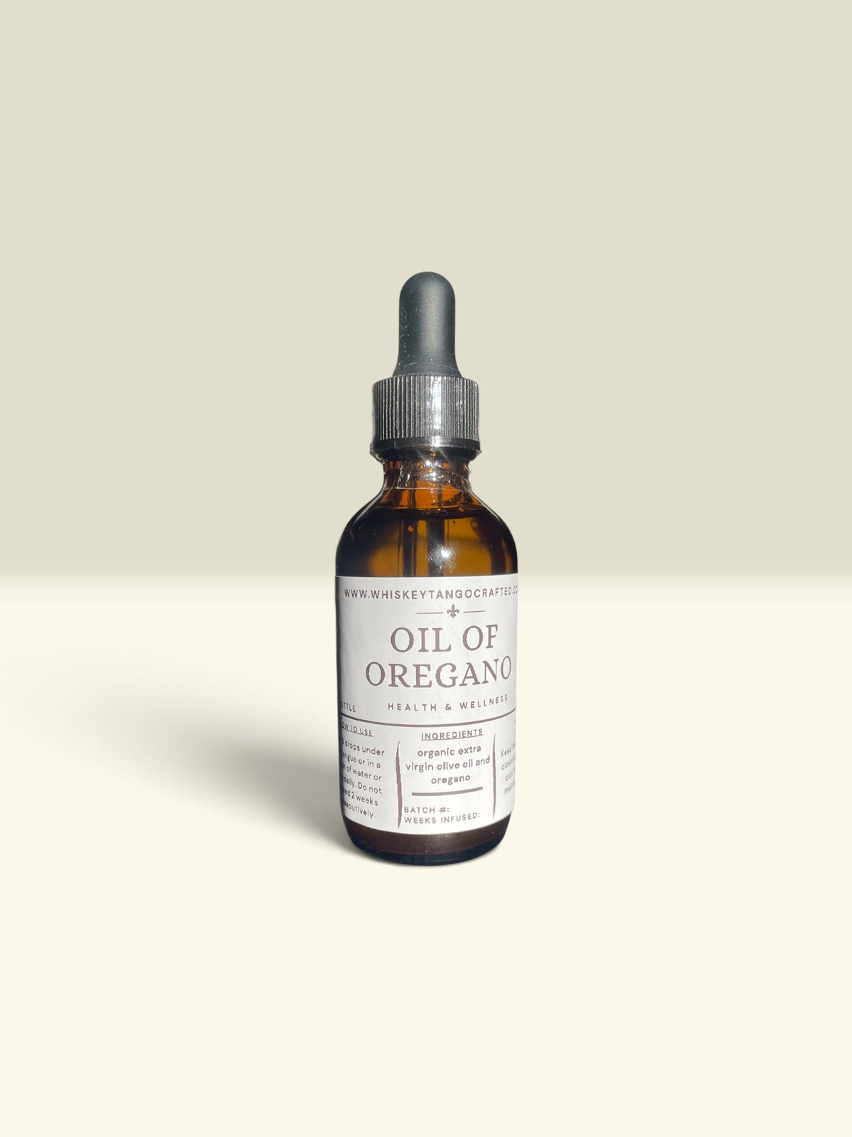 An amber glass dropper bottle of Raw Whiskeystand Organics Oil of Oregano, featuring a white label and a dark gray dropper cap, set against a solid light beige background.