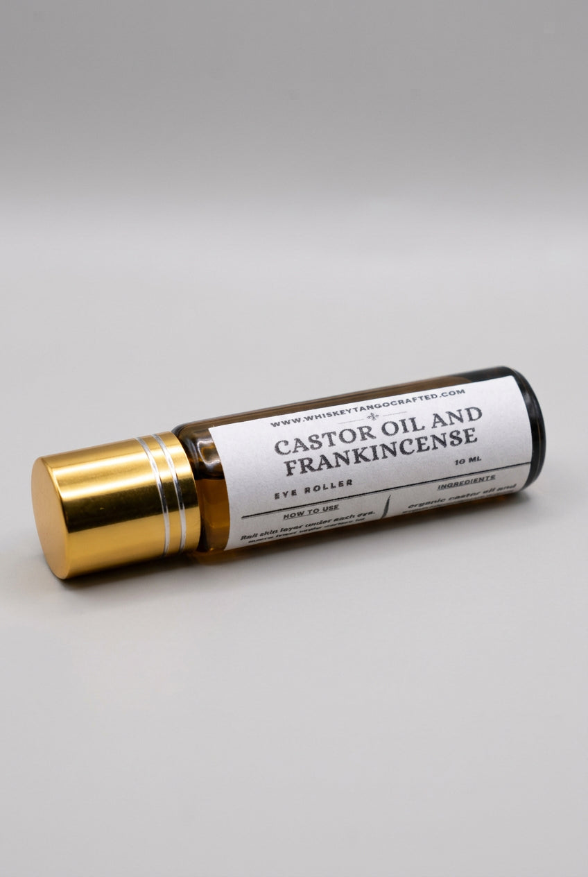 A 10 ml eye roller bottle of Whiskey Tango Crafted Castor Oil and Frankincense, featuring a white label and a gold-toned cap, shown on a light gray background.